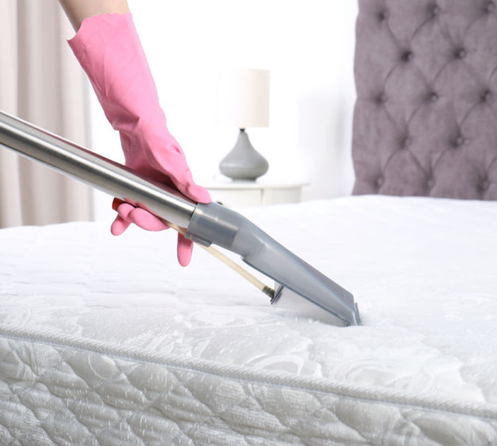 Person vacuuming mattress with gloves